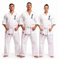 Three martial arts practitioners wearing matching white karate gi uniforms with white belts, standing against a plain white studio background. Each uniform has dark blue Japanese characters on the chest and small red-and-white logo patches near the belt area.