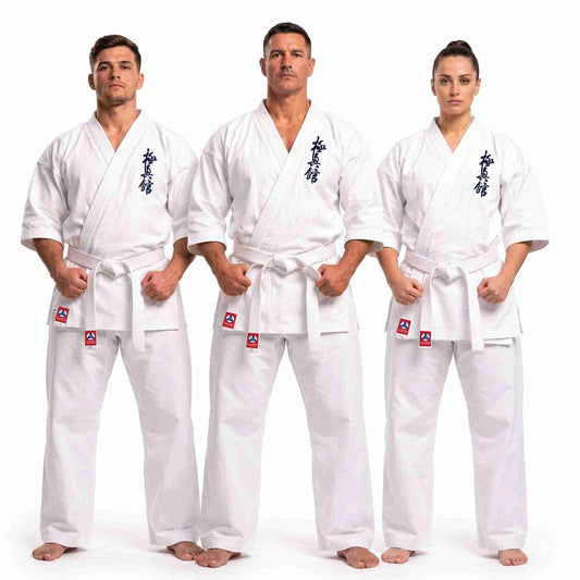 Three martial arts practitioners wearing matching white karate gi uniforms with white belts, standing against a plain white studio background. Each uniform has dark blue Japanese characters on the chest and small red-and-white logo patches near the belt area.